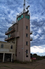 Abandoned Vessel Traffic Service Tower with Lighthouse on The Spurn in Yorkshire with cloudy sky as...