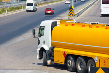 Big heavy yellow truck load of explosive fuel turns and enters a city highway.