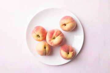 Fresh peaches on white plate with pink background, Summer fruit, Top view