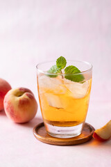 Iced peach tea with mint leaf  in glass and fresh peaches on pink background, Summer drink