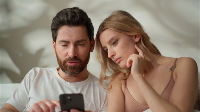 Family Caucasian couple type mobile phone morning together at home partners wife holding device woman playing smartphone game online man speak husband using cyberspace application Internet connection