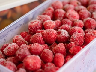 Close-up shot of frozen strawberries in plastic container.