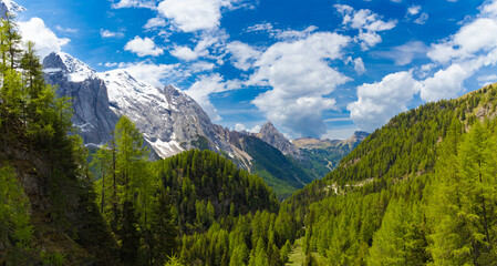 A breathtaking panoramic view of the Dolomites, with the snow-capped Marmolada peaks on the left,...