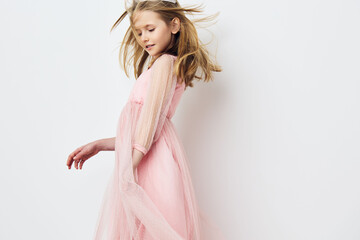 Naklejka premium Young girl in a pink tulle dress joyfully dancing against a white backdrop, embodying innocence and playfulness in a whimsical spring setting