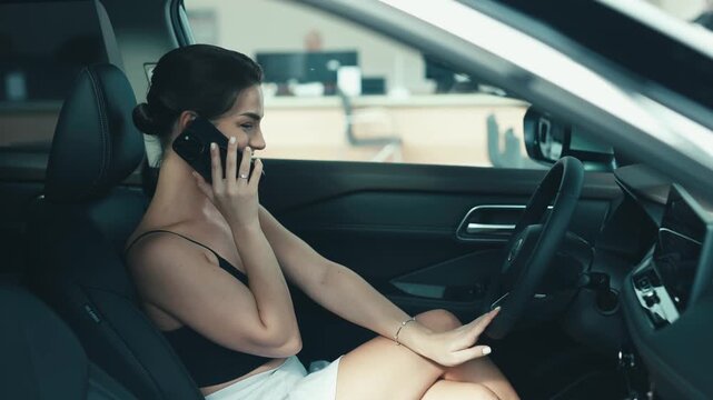 Woman in car dealership is engaged in a phone call while exploring vehicle features, showcasing the car buying experience and decision-making process