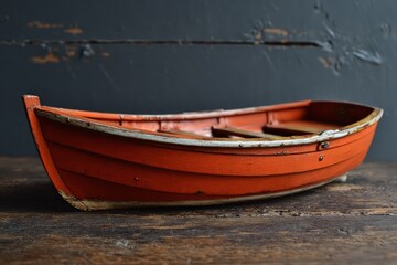 Naklejka premium Vintage Orange Wooden Rowboat On Wooden Surface