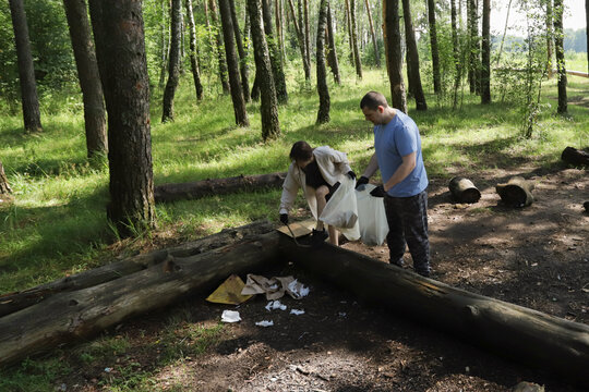 Parent and child working together on forest cleanup, practicing environmental stewardship and teamwork, raising socially responsible youth through outdoor volunteering. - Powered by Adobe