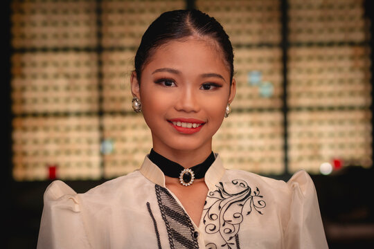 Beautiful Filipina woman smiling warmly in close-up portrait while wearing traditional Filipiniana inside a historic Filipino house.