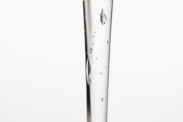 A stream of liquid gel product, hyaluronic acid, peptide on a light background, macro.