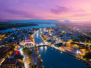 Scenic aerial view of bridge in Hoi An at sunset, illuminated cityscape and tranquil river