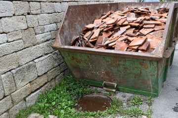 alte Biberschwanz Dachpfannen als Bauschutt in grünem Container