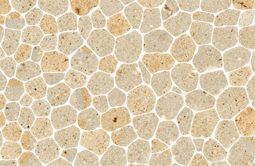 Textured background of light-colored stone pebbles with white grout  