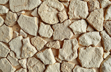 Textured white stone wall made of irregular shaped stones  