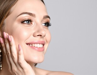 A cheerful woman with flowing long hair and striking blue eyes beams with joy, her radiant smile illuminating her face against a soft, blurred background.