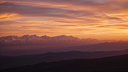 Warm sunset colors highlighting snowy summits and smooth hillsides.