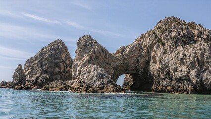 Gigantic textured granite formations lining a scenic pink coast, with large stones near a serene seaside setting in summer.