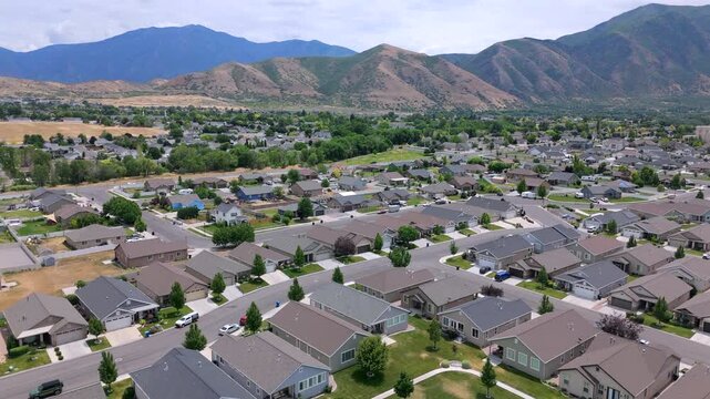 Stunning drone footage captures a serene Salt Lake City suburban community, showcasing an array of charming homes, spacious parks, and breathtaking mountain views. Utah, USA