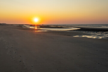 The setting sun reveals the outlines of two people on the almost deserted beach of Terschelling
