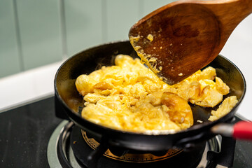 A hand gently folds a fluffy omelet in a pan, beside a perfectly sizzling fried egg. Close-up A hand expertly cooks a golden omelet and a sunny-side-up egg in a hot pan.