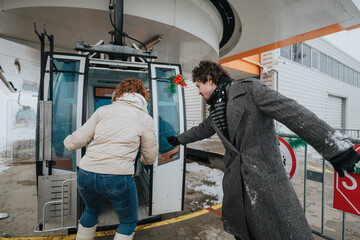 Two friends enjoy a winter outing and prepare to board a gondola amidst snow-covered surroundings. © qunica.com