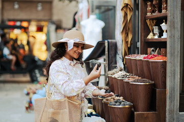 stock image of a young woman wearing floral dress exploring the Dubai creek side Al fahidi spice market, Dubai heritage neighborhood