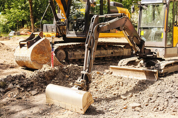 Fototapeta premium Excavator working on construction site. Heavy equipment digging soil. Earthmoving machine on sunny day. Bulldozer in background. Industrial development zone. Land preparation with digging tools.