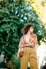 Fototapeta premium A stylish young woman poses outdoors in colorful, retro-inspired fashion, enjoying the day.
