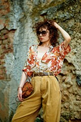 Fototapeta premium A woman with retro fashion poses confidently outdoors, capturing a stylish, vintage vibe.