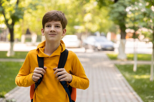 Twelve-year-old boy with a backpack walking to school on a sunny day, symbolizing back to school and education season