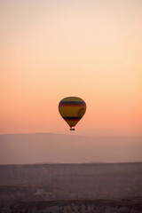 Obraz premium Colorful Hot Air Balloon Soaring Over a Rocky Landscape