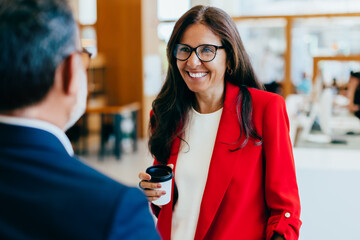 Professional woman smiling while conversing with colleague in business environment