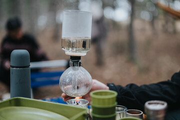Cozy winter picnic in the mountains showcasing a siphon coffee brewing system amidst a serene outdoor setting.