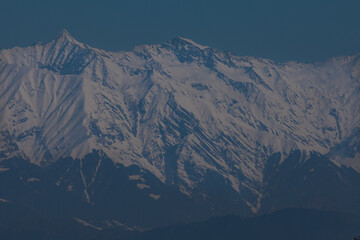Snow covered dhauladhar mountain peaks under blue sky. A breathtaking close-up image of the majestic Dhauladhar mountain peaks blanketed in snow beneath a crystal-clear blue sky.