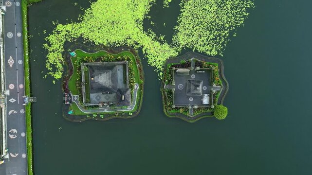Aerial view of the serene Danau Beratan temple islands contrasts with the surrounding deep green water and light green vegetation, Candikuning, Kabupaten Tabanan, Indonesia.