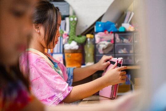 Two elementary school girls are studying at their desks at home. Two cute schoolgirls are diligently doing their homework.