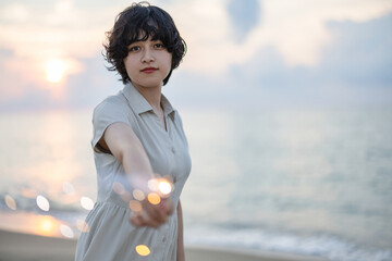 夕暮れの海辺で花火を楽しむ女性モデルの柔らかなボケ感を活かしたポートレート