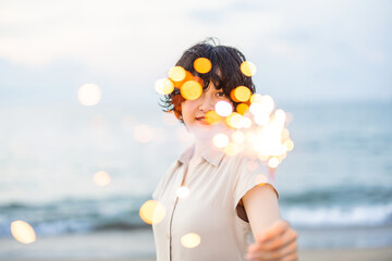 夕暮れの海辺で花火を楽しむ女性モデルの柔らかなボケ感を活かしたポートレート