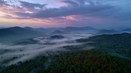 Fototapeta premium Morning fog rolling over dense green forested hills under cloudy sky