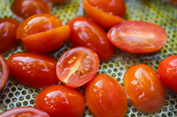 Close-up of fresh juicy cherry tomatoes, sliced in half, being prepared for cooking. Healthy eating and food background concept