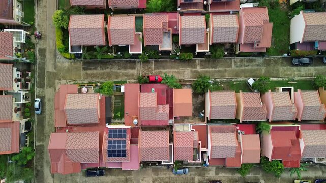 Drone drifts back and up above Bancao-Bancao terracotta roofs, revealing lush forest fringe, Puerto-Princesa Bay with boats and hazy mountain silhouettes on the horizon.