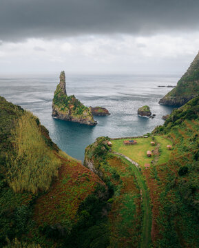 Aerial view of a dramatic coastline where jagged cliffs meet the turquoise ocean under a moody sky, Ba&Atilde;&shy;a da Alagoa, Portugal.