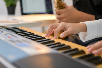 Obraz premium Two young Asian man and woman performing music indoors with keyboard and saxophone