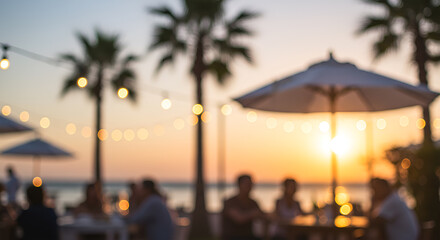 Blurred outdoor scene of people dining, palm trees, and sunset.