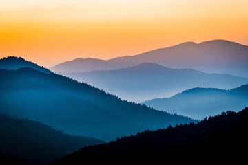 Fototapeta premium Majestic blue and purple mountain silhouettes layered at sunset with an orange sky