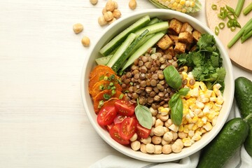 Healthy vegetarian food. Delicious Buddha bowl and ingredients on light wooden table, flat lay. Space for text