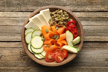 Healthy vegetarian food. Delicious Buddha bowl with lentils, tofu and vegetables on wooden table, top view