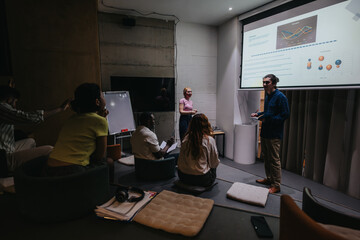Group of colleagues engaged in a business discussion, with presentation visuals and diverse perspectives contributing to strategic planning in a modern office setting