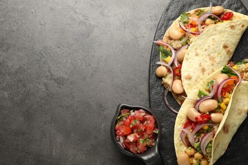 Tasty vegetarian tacos with beans and quinoa served on grey table, top view. Space for text