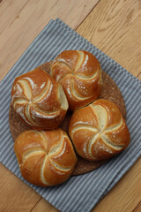 Top view of decorated bread rolls on gray striped napkin on wooden table