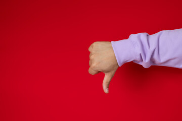 Male hand making thumbs down gesture on a red background, disapproval concept